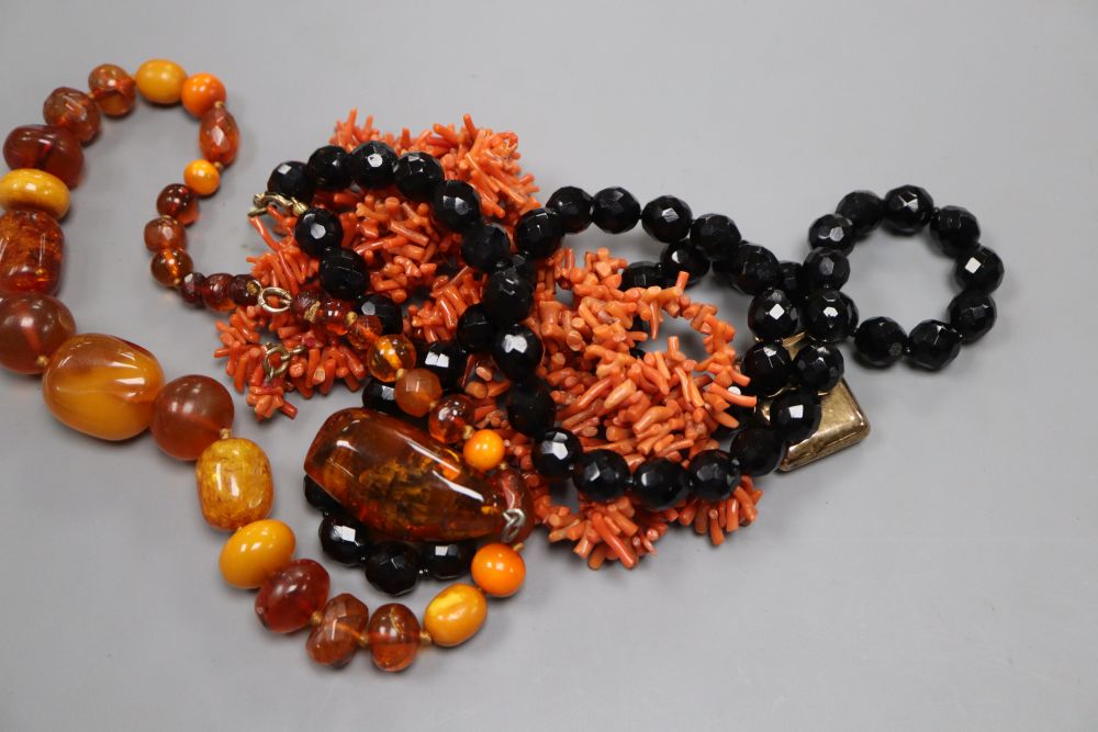 Four assorted necklaces including amber and coral, an amber pendant and a yellow metal locket (a.f.).
